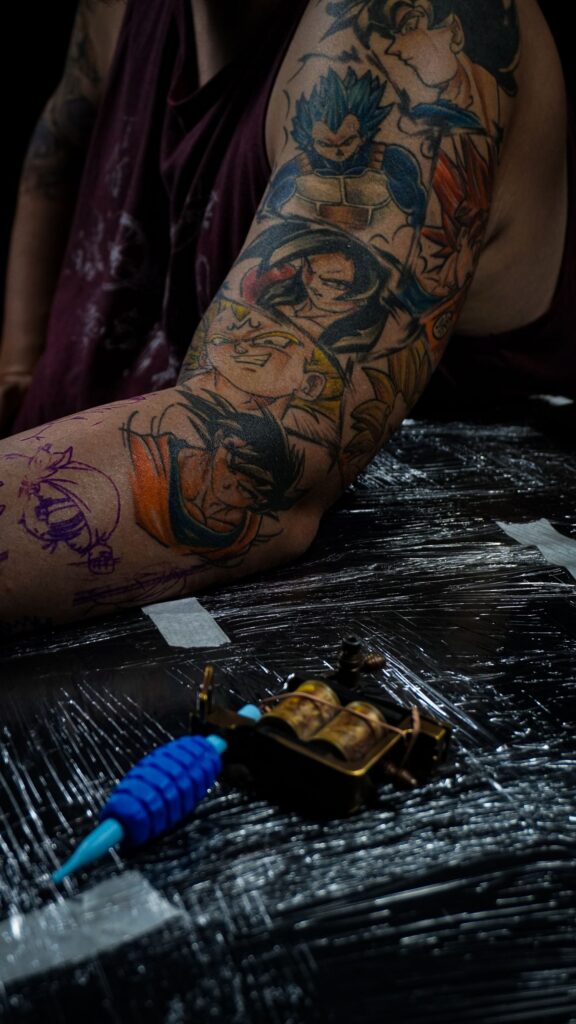 Close-up of a colorful anime-themed arm tattoo in a tattoo studio setting.