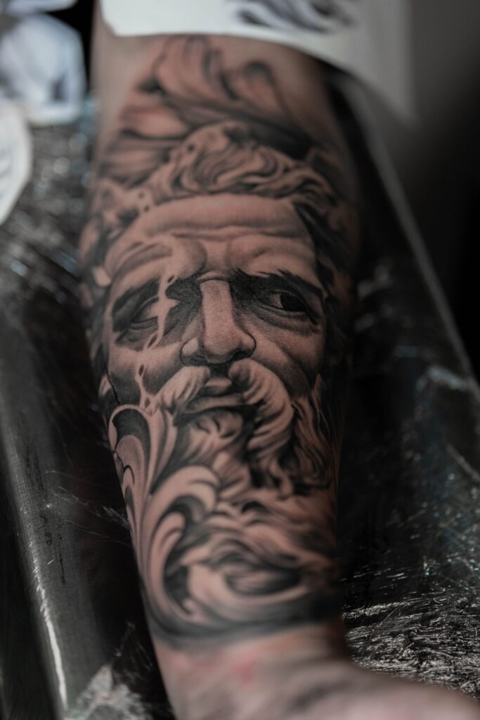 Close-up of a detailed Zeus tattoo on a person's forearm, emphasizing artistic design.