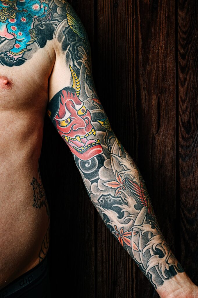 Colorful tattoo sleeve on a man's arm against a wooden background.