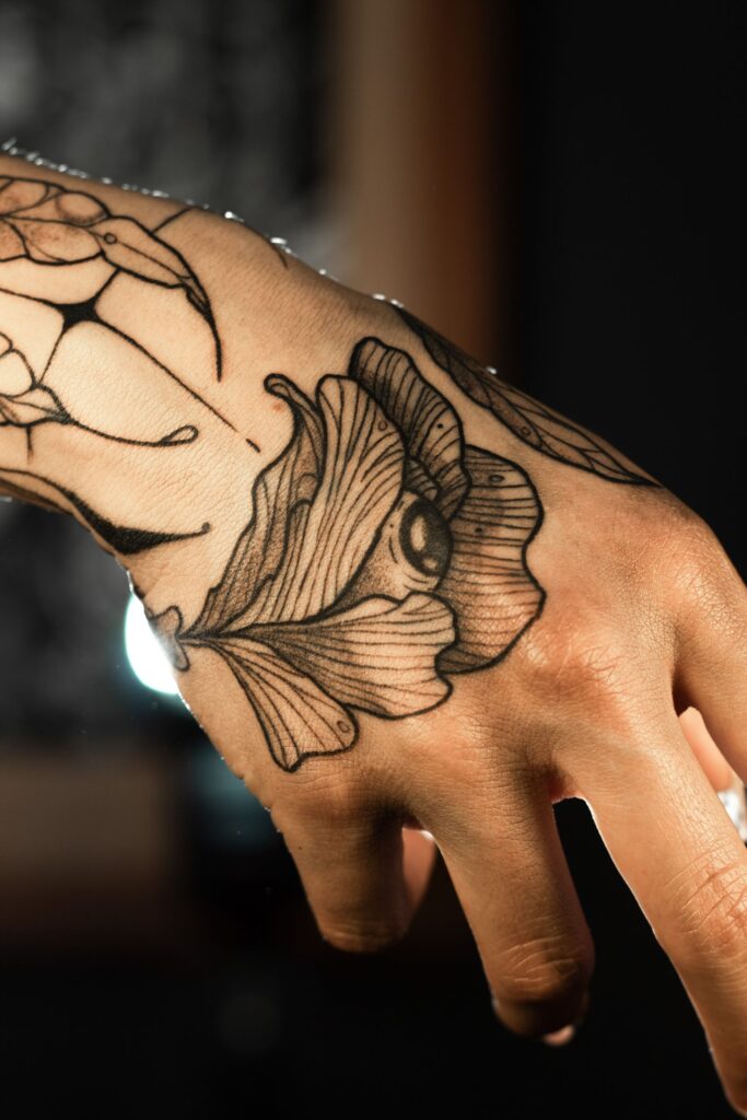 Detailed tattoo artwork on a hand showcasing a flower design in a close-up shot.