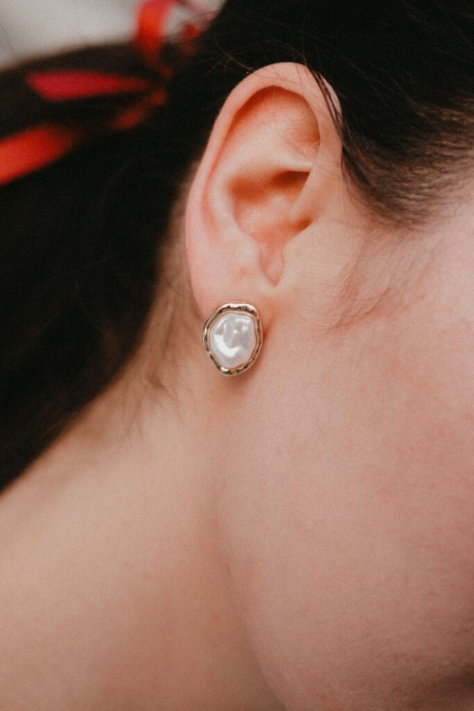 Detailed view of a woman's ear wearing a stylish pearl earring.