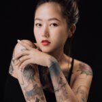 Portrait of a tattooed woman with red lips posing in a studio.