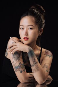 Portrait of a tattooed woman with red lips posing in a studio.