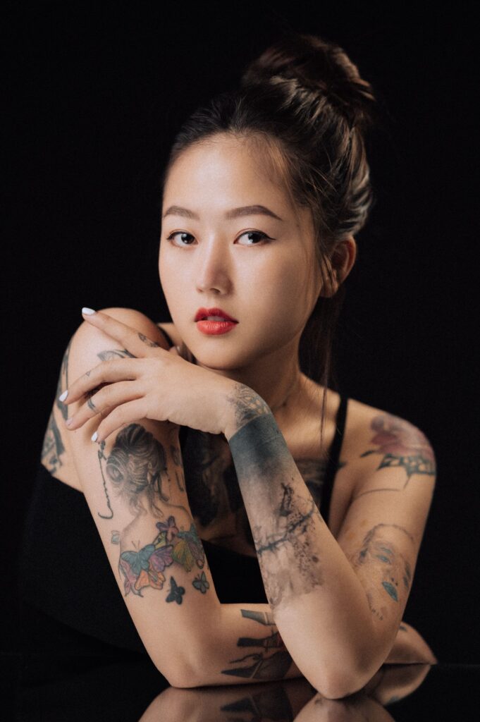Portrait of a tattooed woman with red lips posing in a studio.