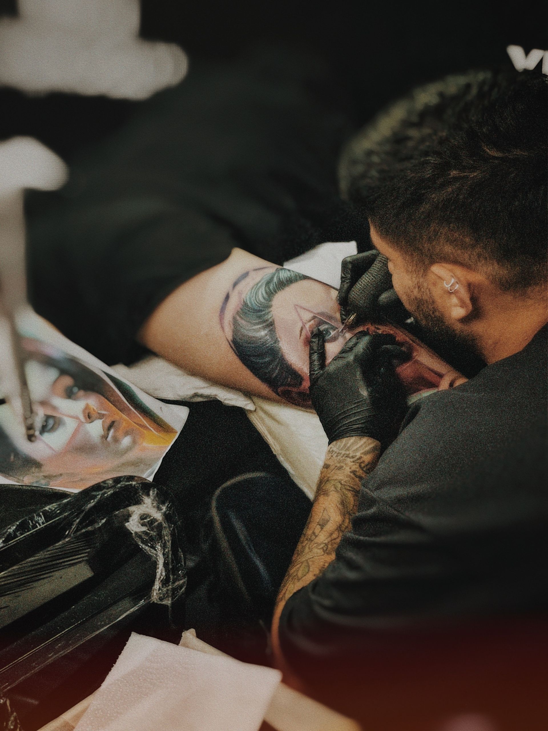 Tattoo artist skillfully inks a realistic portrait on a client's arm, capturing fine details.