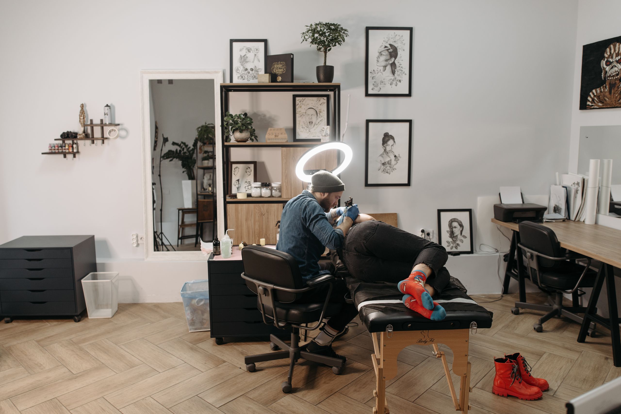Tattoo artist using a tattoo machine in a stylish studio, focusing on intricate design.