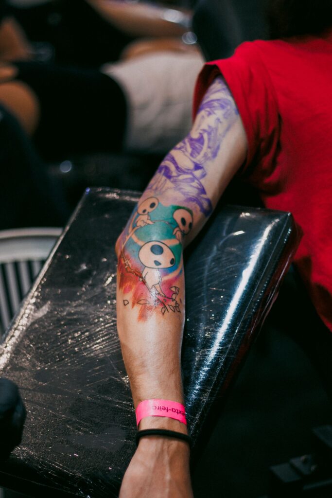 Vibrant arm tattoo featuring cartoon faces at a tattoo parlor.